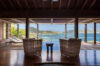 Covered lounge with wicker chairs facing infinity pool and ocean view at St Barts villa rental