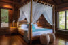 Elegant four-poster bed with white canopy in wooden suite at luxury villa in St Barts
