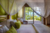 Tropical bedroom in a St Barts villa with canopy bed, garden view and sliding doors to the terrace