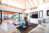 Bright living room of a St Barts villa with white sofas, vaulted ceiling, and open terrace leading to the garden pavilion.