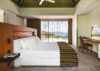 Elegant bedroom in a St Barts villa with modern design, sea views through sliding glass doors, and warm wooden accents.