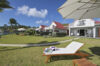 Beachfront villas with red roofs, private balconies, and sun loungers on a green lawn in St Barts vacation rentals.