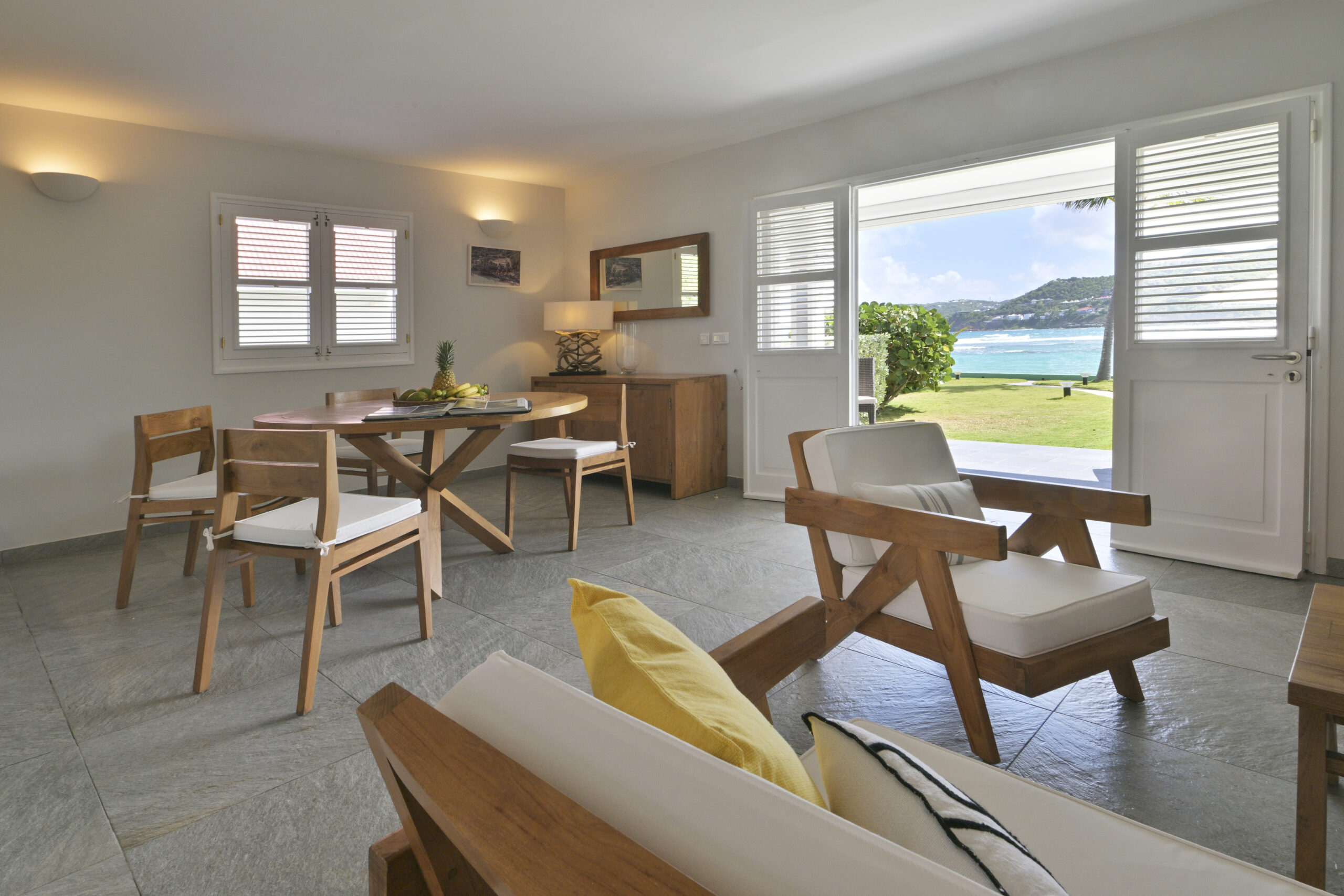 Open-plan living and dining room with wooden table, modern kitchen, and staircase inside a St Barts villa rental.