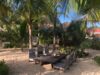 Rustic outdoor dining table set in the sand beneath palm trees at a private St Barts villa