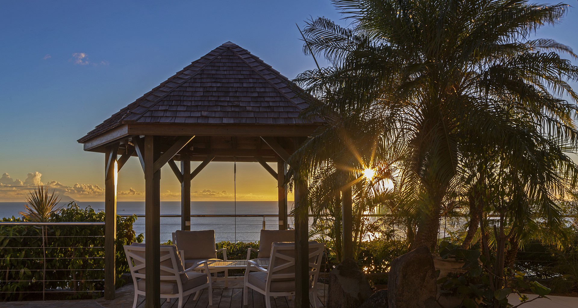 Gazebo with seating facing ocean sunset and palm trees at St Barthelemy villa rental