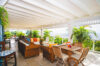 Covered terrace in St Barths villas with lounge seating, dining tables, and ocean view