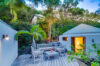 Cozy outdoor terrace in St Barts villa with wooden deck seating, palm trees, and garden lighting at dusk
