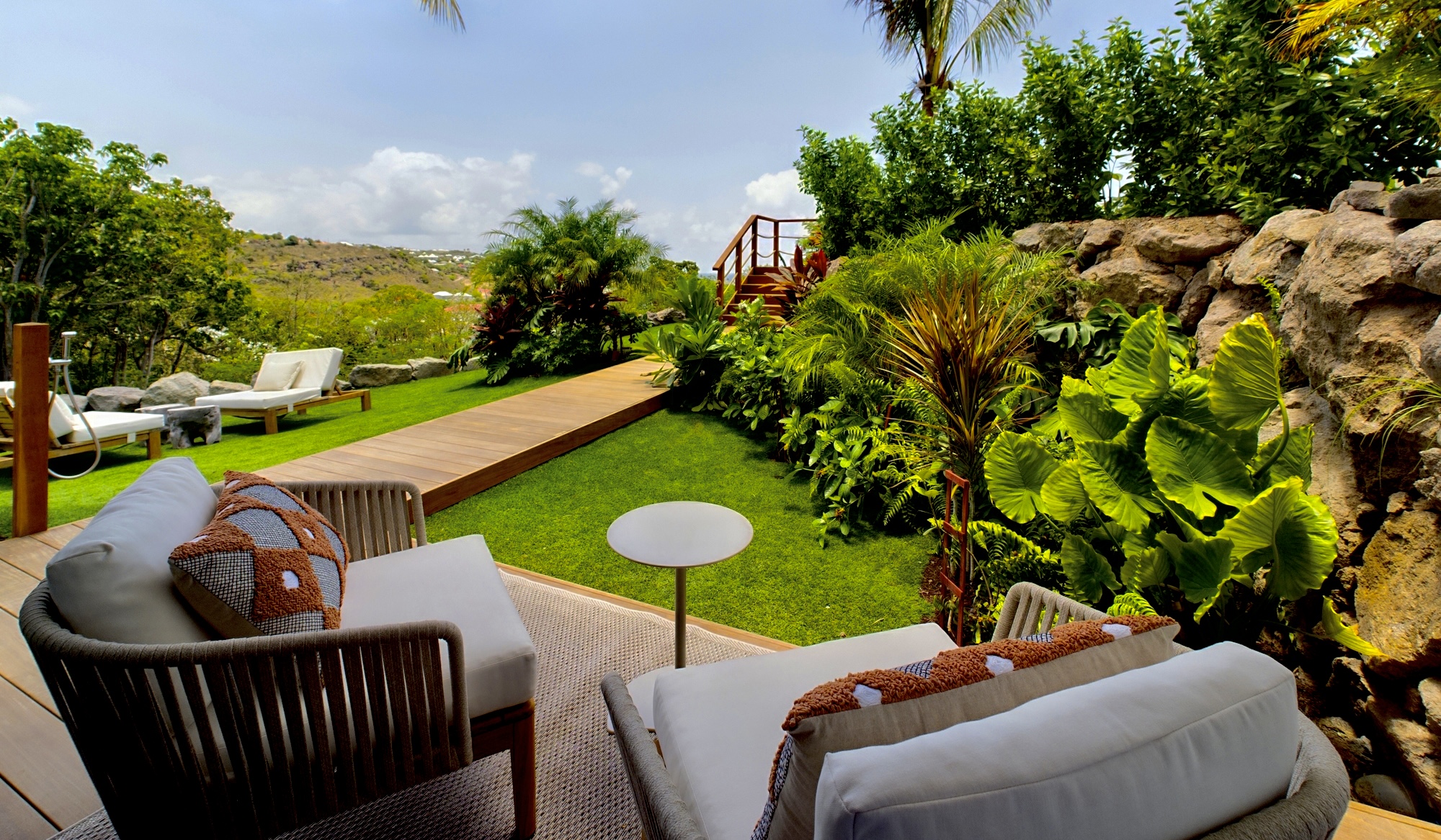 Relaxing garden terrace at a St Barts villa rental with cushioned seating and tropical greenery.
