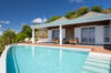 St Barts villa with turquoise infinity pool, sun loungers, and covered terrace framed by tropical hillside