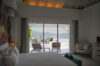 Bedroom in a St Barts villa with sliding glass doors opening to a terrace, pool, and panoramic ocean views.