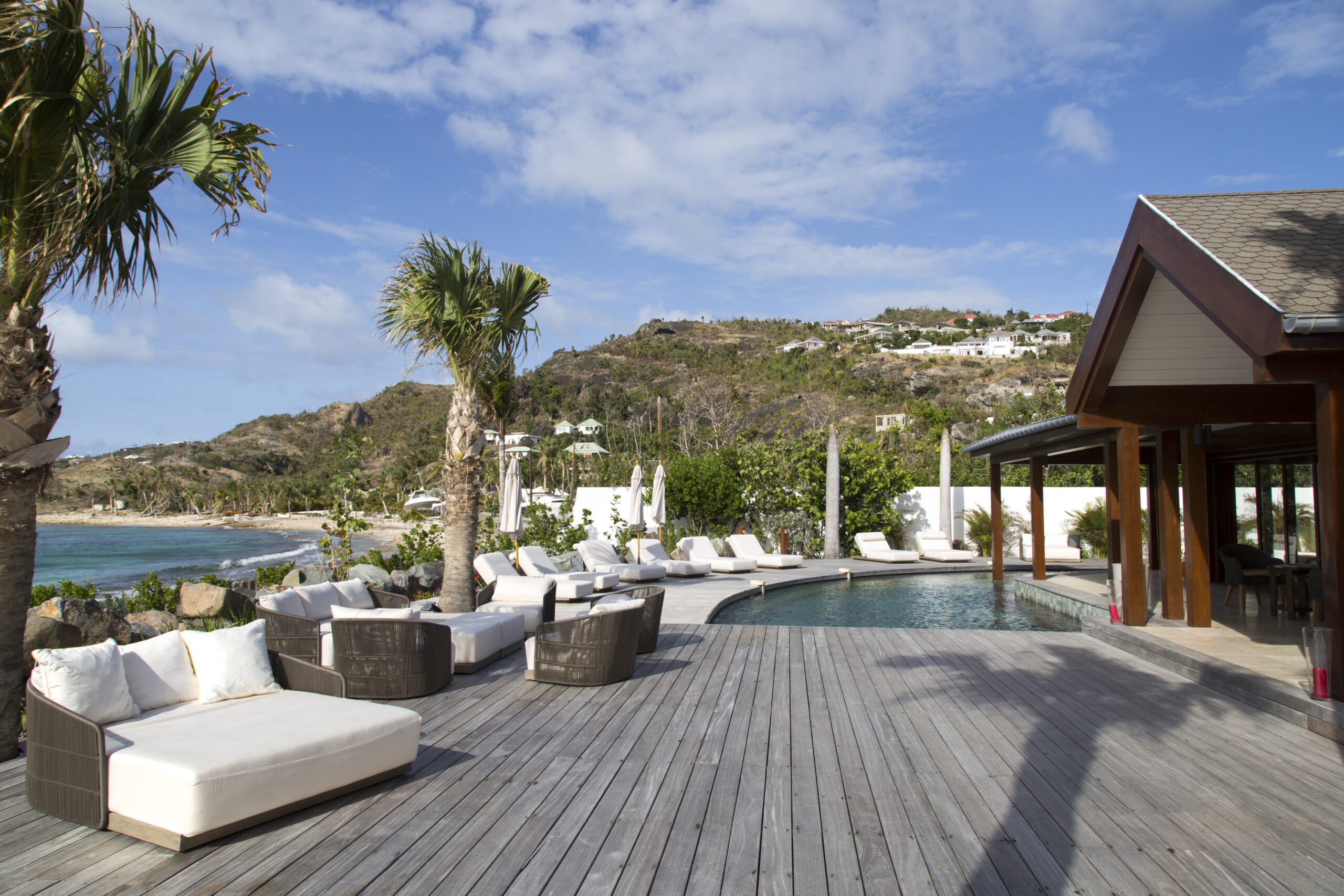 Spacious pool deck with lounge chairs, ocean views, and hillside backdrop at a luxury villa in St Barts