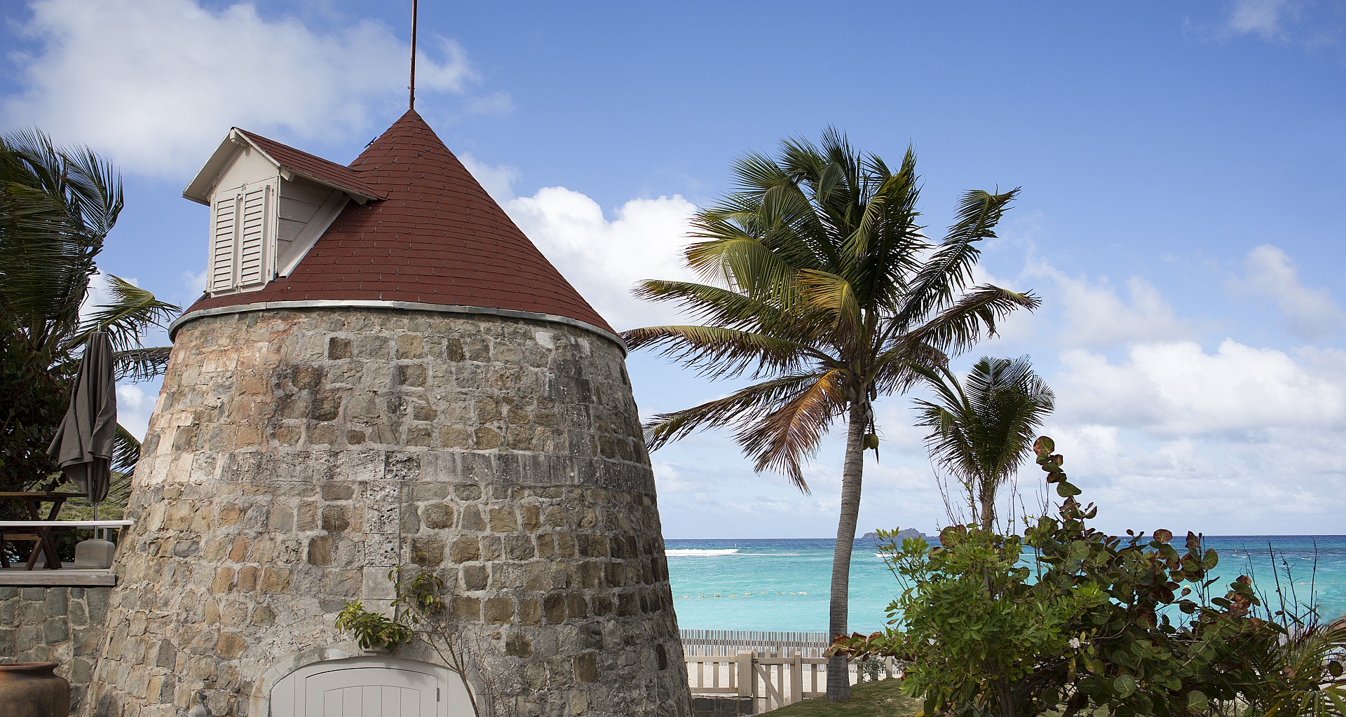 Rustic stone windmill villa in St Barts with shaded terrace and views over the Caribbean Sea.