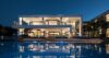 Contemporary St Barts villa illuminated at night with expansive glass design and pool reflecting the architecture.
