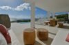 Covered lounge terrace with ocean views, wooden furniture, and poolside seating at a St Barts villa rental.