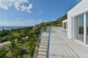 Spacious villa terrace with pool and ocean views surrounded by lush hills in St Barts.