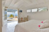 Bright bedroom with white decor opening to a terrace with pool and ocean views in a St Barts villa rental.