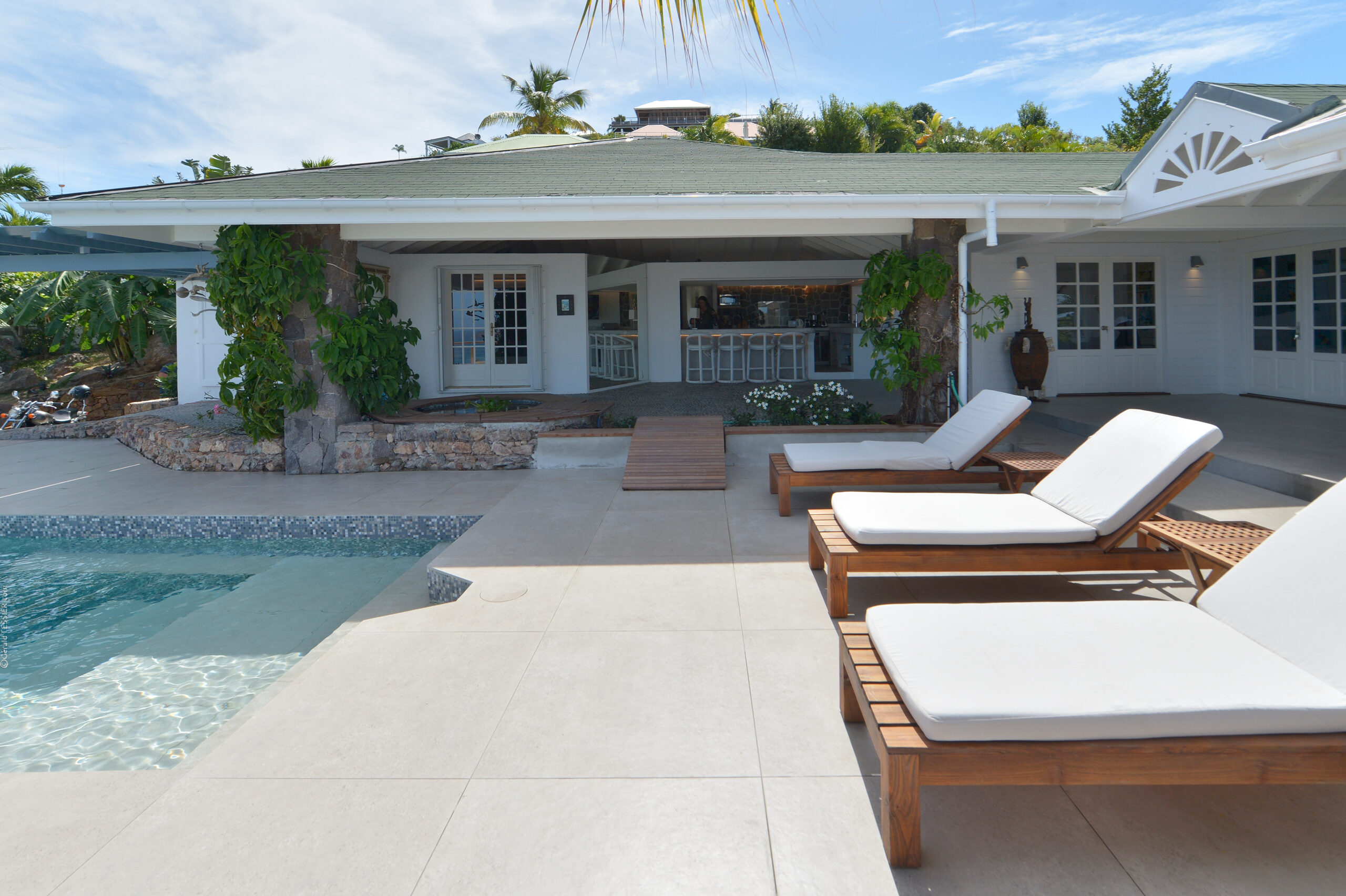 Villa exterior with mosaic-tiled pool, shaded pergola, and sun loungers in a private St Barts vacation rental.