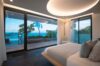 Elegant bedroom in a St Barts villa with modern lighting, glass doors, and sweeping ocean views