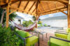 Shaded gazebo at a St Barts villa with hammock, green cushioned seating, and view of the private pool.