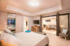 Cozy bedroom in a St Barts villa with modern design, flat-screen TV, and sliding doors opening to the living area.