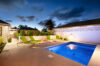 Evening view of a private villa pool in St Barts with green sun loungers and tropical garden setting.