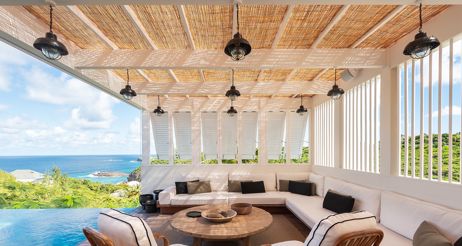 Shaded outdoor lounge in villa st barths with ocean view and infinity pool.