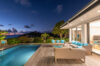 Terrace lounge of a St Barts villa with pool, turquoise cushions, and panoramic sunset views over the Caribbean Sea.