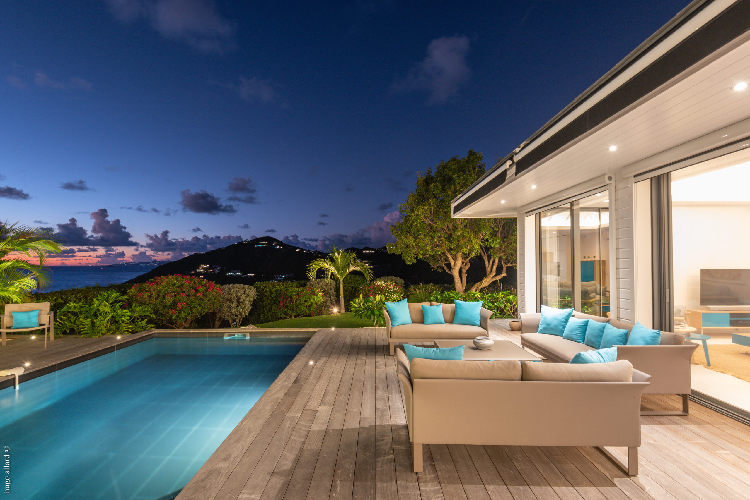 Terrace lounge of a St Barts villa with pool, turquoise cushions, and panoramic sunset views over the Caribbean Sea.
