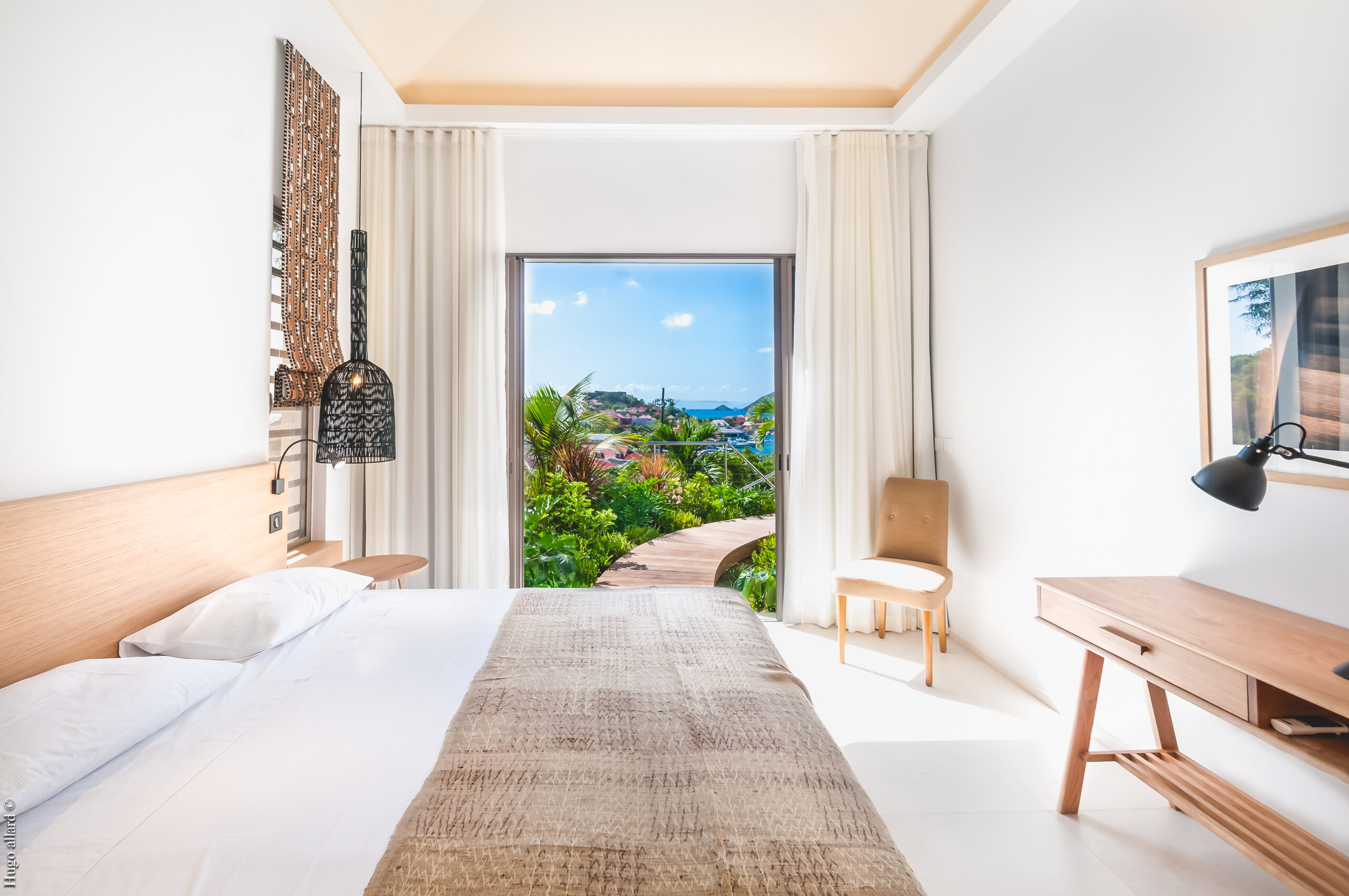 Bright bedroom in a St Barts villa rental with terrace view of tropical gardens and ocean horizon.