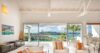Modern St Barts villa living room with plush seating and panoramic ocean views through glass doors.