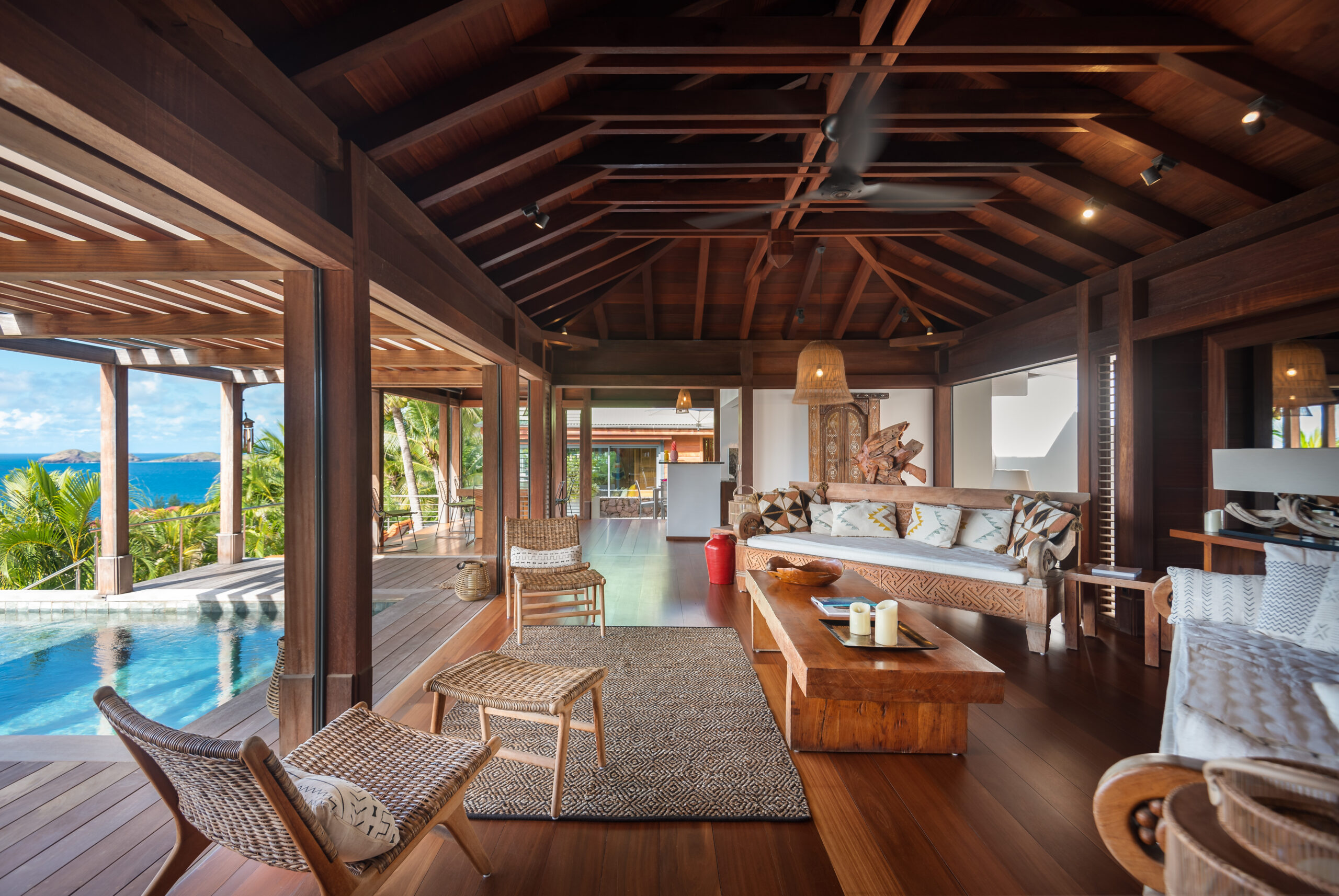Spacious open-air living room with wooden interiors and poolside views at a luxury villa in St Barts.