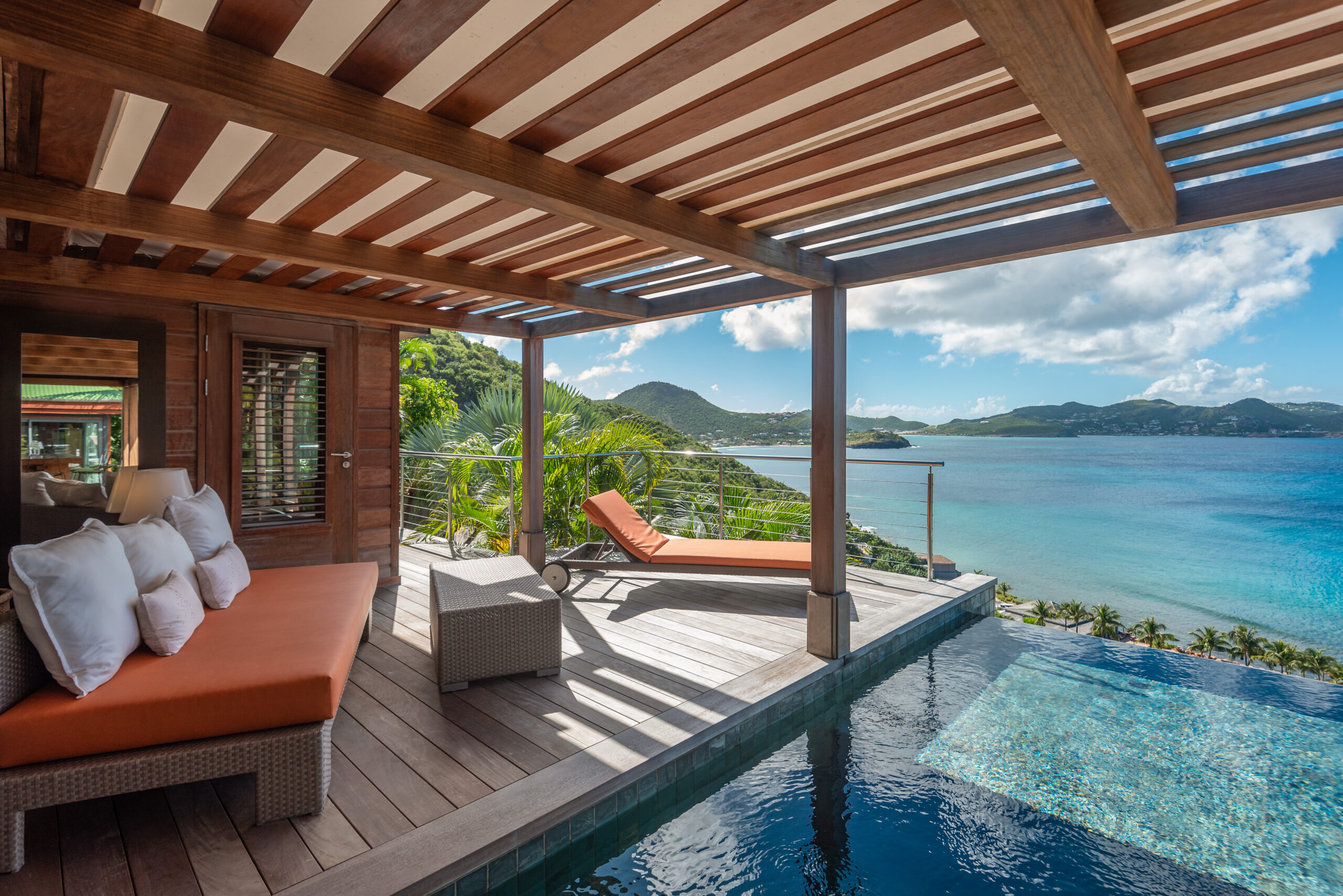 Shaded deck with daybeds and infinity pool overlooking turquoise waters in a luxury St Barts villa rental.