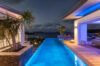 Evening view of illuminated infinity pool with ocean horizon at a luxury St Barts villa rental.