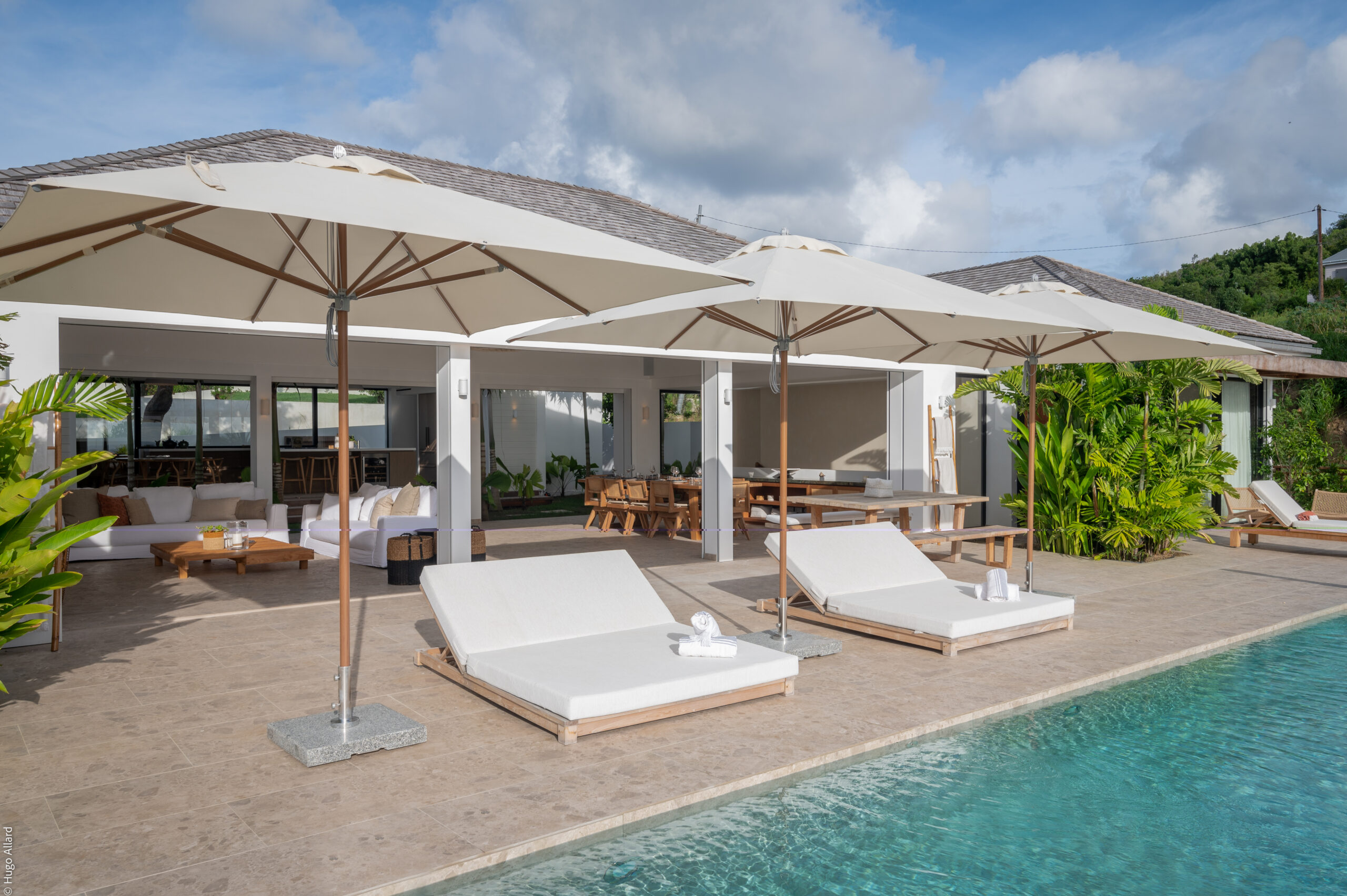 Poolside terrace at St Barts villa with sun loungers, umbrellas, and open-air living spaces, vacation rental St Barthelemy