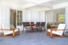 Covered terrace in a St Barts villa with wooden armchairs, dining table, and seamless access to indoor lounge.
