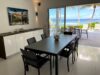Dining area in a St Barts villa with sleek black table, glass doors to terrace, and panoramic ocean views.