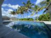 Seaside St Barts villa with pool reflecting palm trees, stone walls, and views of the Caribbean horizon.
