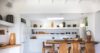 Minimalist white kitchen with wooden dining table and modern pendant lights in a St Barths villa rental.