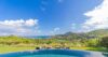 Infinity pool at a St Barts villa with sun loungers on the lawn and sweeping ocean and hillside views.
