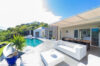 Luxury St Barts villa terrace with outdoor seating, dining area, and pool surrounded by lush tropical hillside.