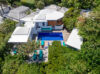 Aerial view of a private St Barts villa with turquoise loungers, lush tropical gardens, and a central swimming pool