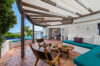 Shaded terrace lounge with built-in seating, rustic chairs, and garden views in a St Barts vacation rental.