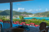 Covered terrace dining table overlooking pool loungers and turquoise bay views at a hillside St Barts villa rental.