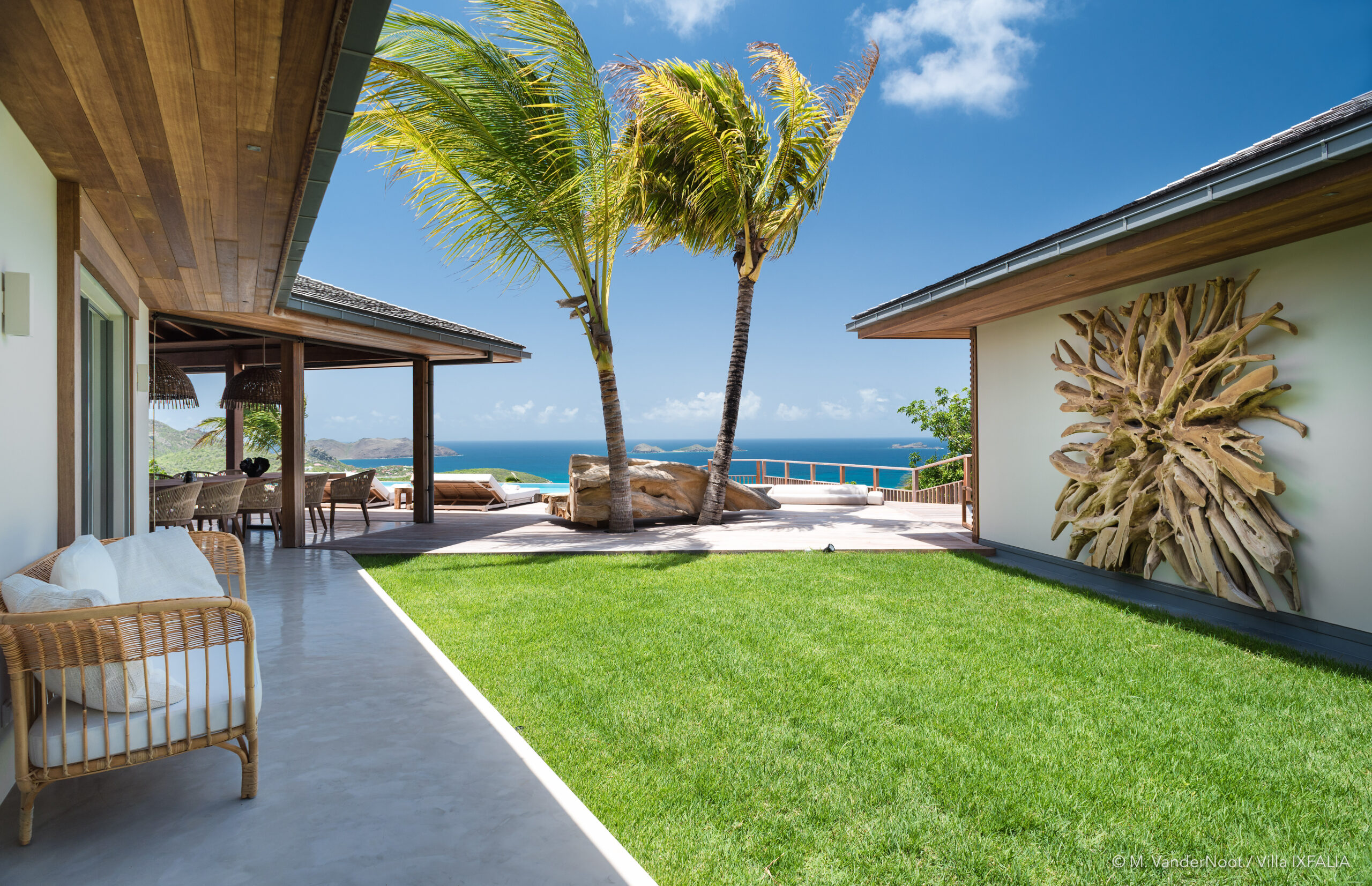 A picturesque view of Villa Ixfalia in St. Barts, showcasing the gentle sea breeze and swaying palm trees.