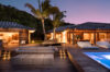Twilight pool terrace at a luxury St Barts villa with palm trees and elegant lounge seating.