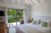 Sunlit bedroom in a St Barts villa rental with garden view and sliding doors opening to the terrace