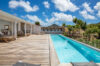 Long swimming pool with wooden deck, sun loungers, and hillside views at a private St Barts villa rental.