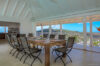 Covered dining terrace with wooden table, seating for eight, and panoramic hillside views at a St Barts villa rental.