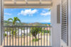 Balcony with white shutters overlooking palm trees, hills, and distant ocean views at a St Barts villa rental.