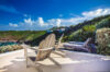 Sunny terrace with wooden lounge chairs overlooking lush hills and the Caribbean Sea in St Barts villa rental